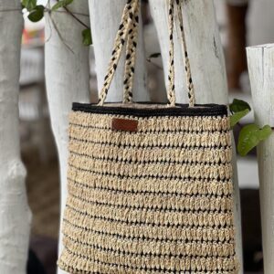 Photo d'un totebag accroché à une branche en bois en raphia crocheté, artisanat de madagascar, muni de grande anse en raphia tressé, entièrement fait main, couleur naturel et noir