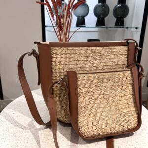 Photo de deux sacs à mains de ville de différentes tailles, posé sur une table en marbre, sac en raphia crocheté avec une bande de cuir naturel sur le côté, muni d'une bandoulière amovible en cuir naturelle couleur camel, idéale pour les sorties en ville.