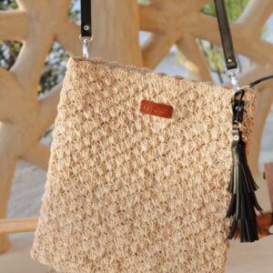 Photo de sac en raphia crocheté suspendu, couleur naturelle et point ananas, muni d'une grande anse amovible en cuir véritable de couleur noir et fermé par une fermeture