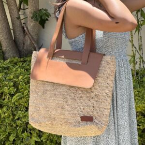 Photo d'un sac à main SOA grand modèle porté épaule par une jeune femme, en raphia naturel avec rabat en cuir véritable couleur camel, artisanat de Madagascar, réalisé au crochet, idéal pour une sortie en ville.