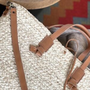 Photo d'un grand panier en raphia tressé porté main panier raphia avec une grande bandoulière en cuir naturel couleur camel. Artisanat de Madagascar, entièrement réalisé à la main.