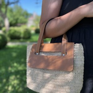 Photo d'un sac à main en raphia naturel avec rabat en cuir véritable couleur camel, porté main, artisanat de Madagascar, réalisé au crochet, idéal pour une sortie en ville.