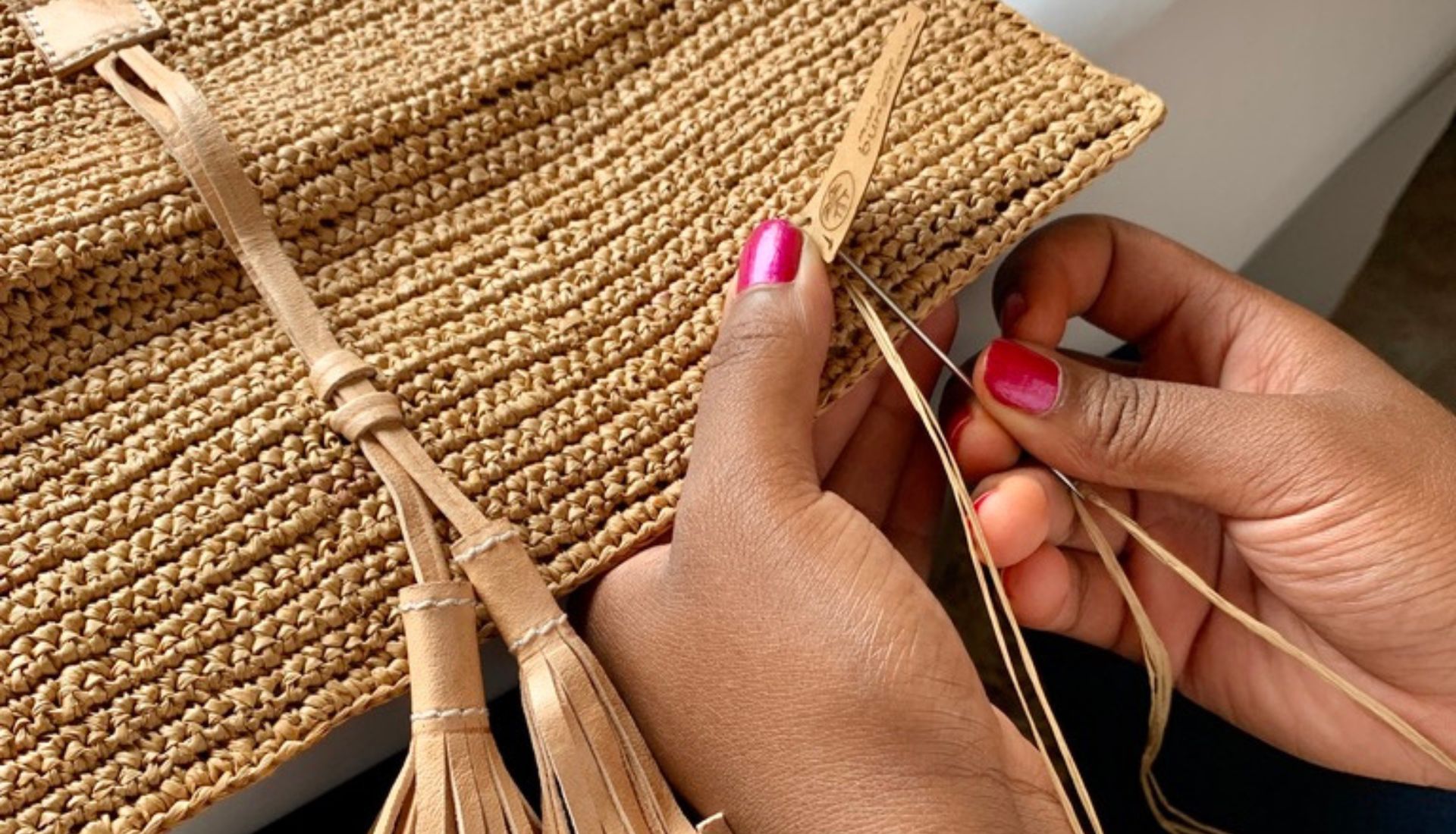 Photo d'une femme en plein tissage d'une pochette en raphia de Madagascar.