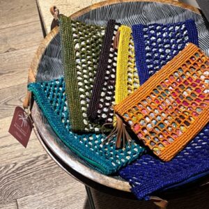 Photo de pochettes en raphia GIPSY, plusieurs coloris jaune, vert, kaki, orange, bleu indigo,aubergine, doublé tissu imprimé, artisanat de Madagascar. Style bohème.